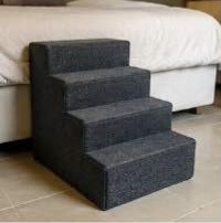 Four-step grey carpeted pet stairs next to a bed
