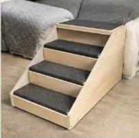 Wooden pet stairs with carpeted treads leading up to a bed